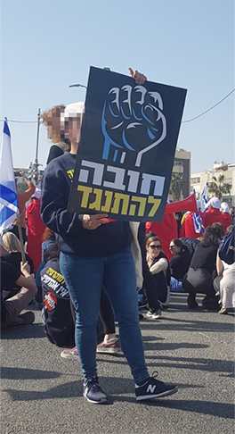 מפגינה עם שלט, עם כיתוב ״חובה להתנגד״