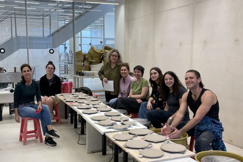 מרצים ומרצות, סטודנטים וסטודנטיות יושבים בחדר אובניים במחלקה ומולם עשרות צלחות קרמיות שהכינו