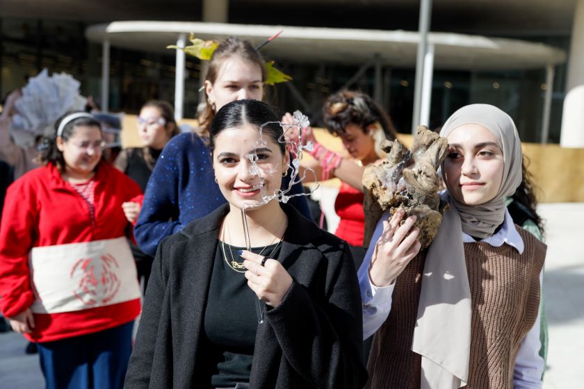 נשים צעירות באירוע מחזיקות יצירות אמנות ליד פניהן