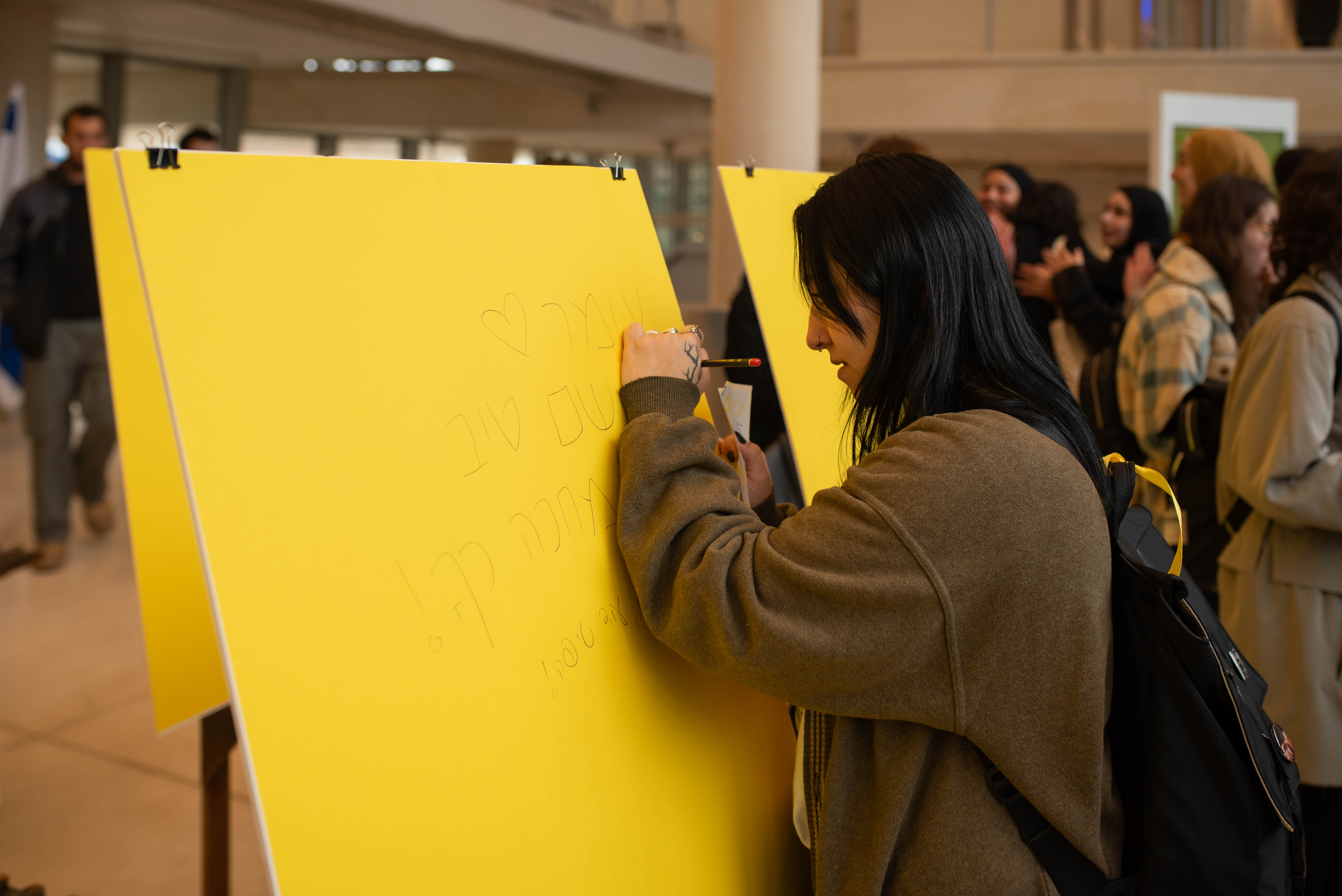 סטודנטים כותבים על גליונות נייר צהובים העומדים ברחבה המרכזית