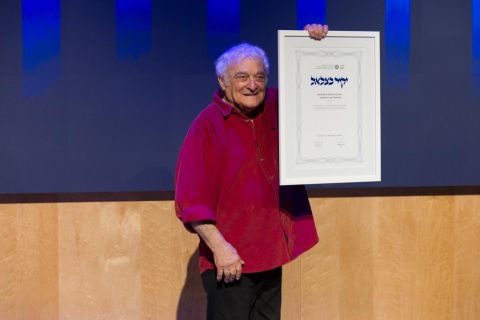 פרופ׳ צבי טולקובסקי אוחז בידיו את אות יקיר בצלאל, תעודה ממוסגרת.