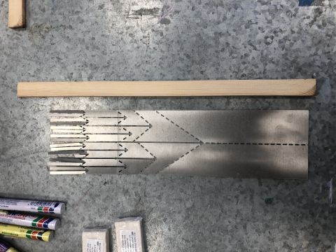 שולחן ועליו טושים, מקלות עץ ומשטח אלומיניום דק
