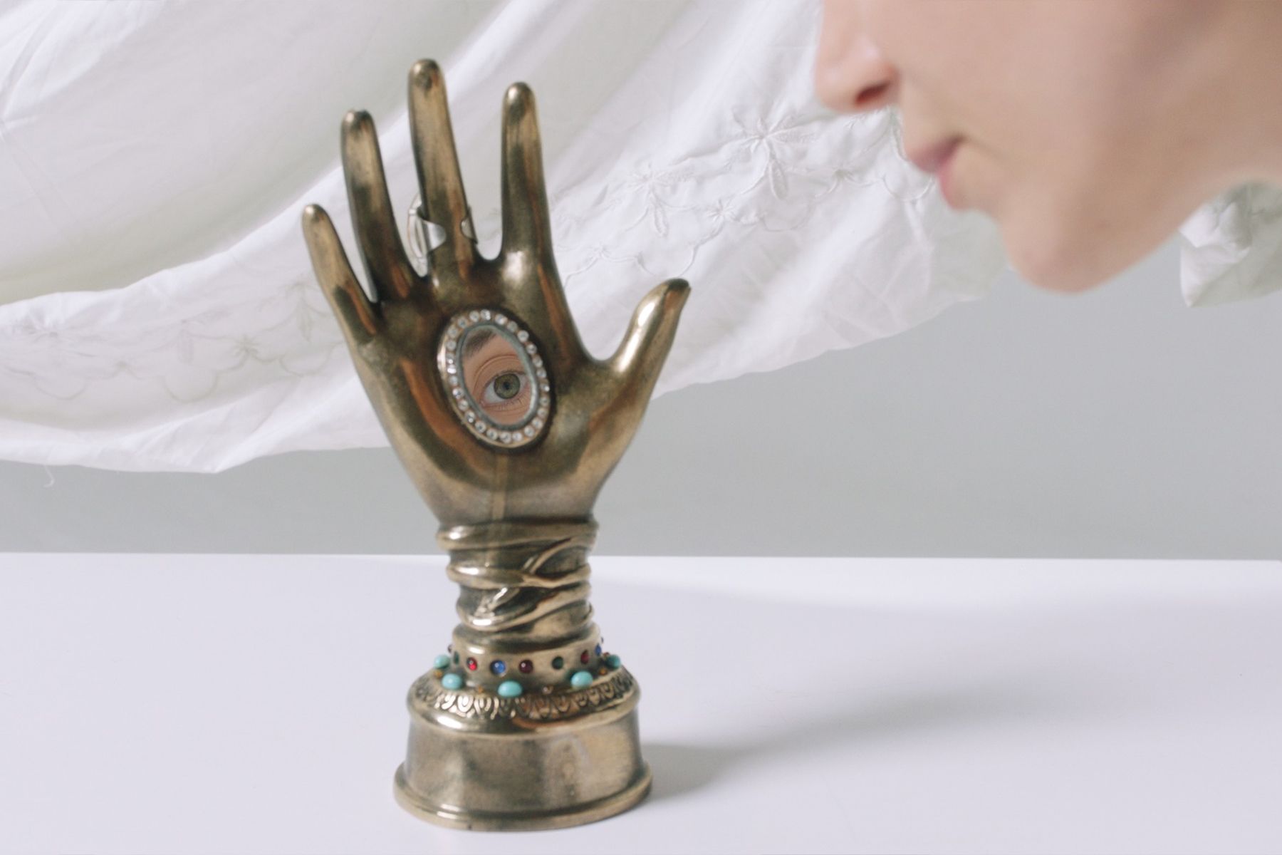 פסל כף יד עשויה ממתכת, עם מראה קטנה שבה משתקפת עין אנושית, ׳Nexus׳, מיצב וידיאו/סאונד, אלנה צ'רטי שטיין, 2022