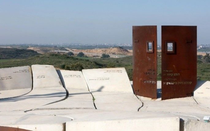 שתי דלתות מתכת חלודה על גבי לוחות אבן חרוטים, צופות לנוף