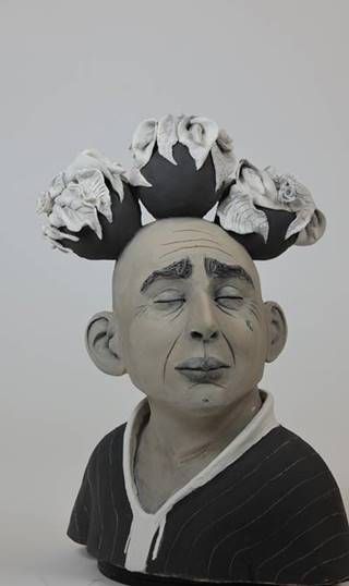 עיצוב קרמיקה של דמות איש עם כדי פרחים על הראש